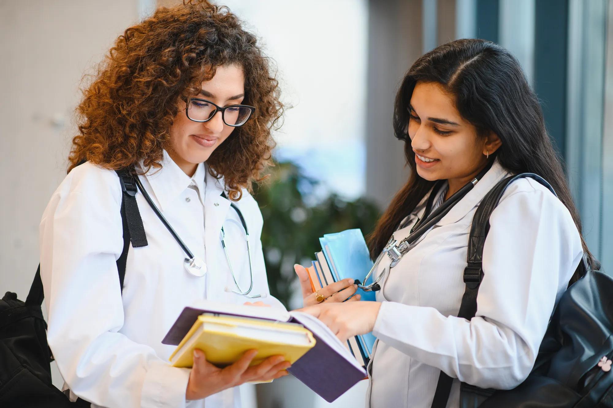 Two young female medical students discussing subjects and preparing for class, walking in a university building