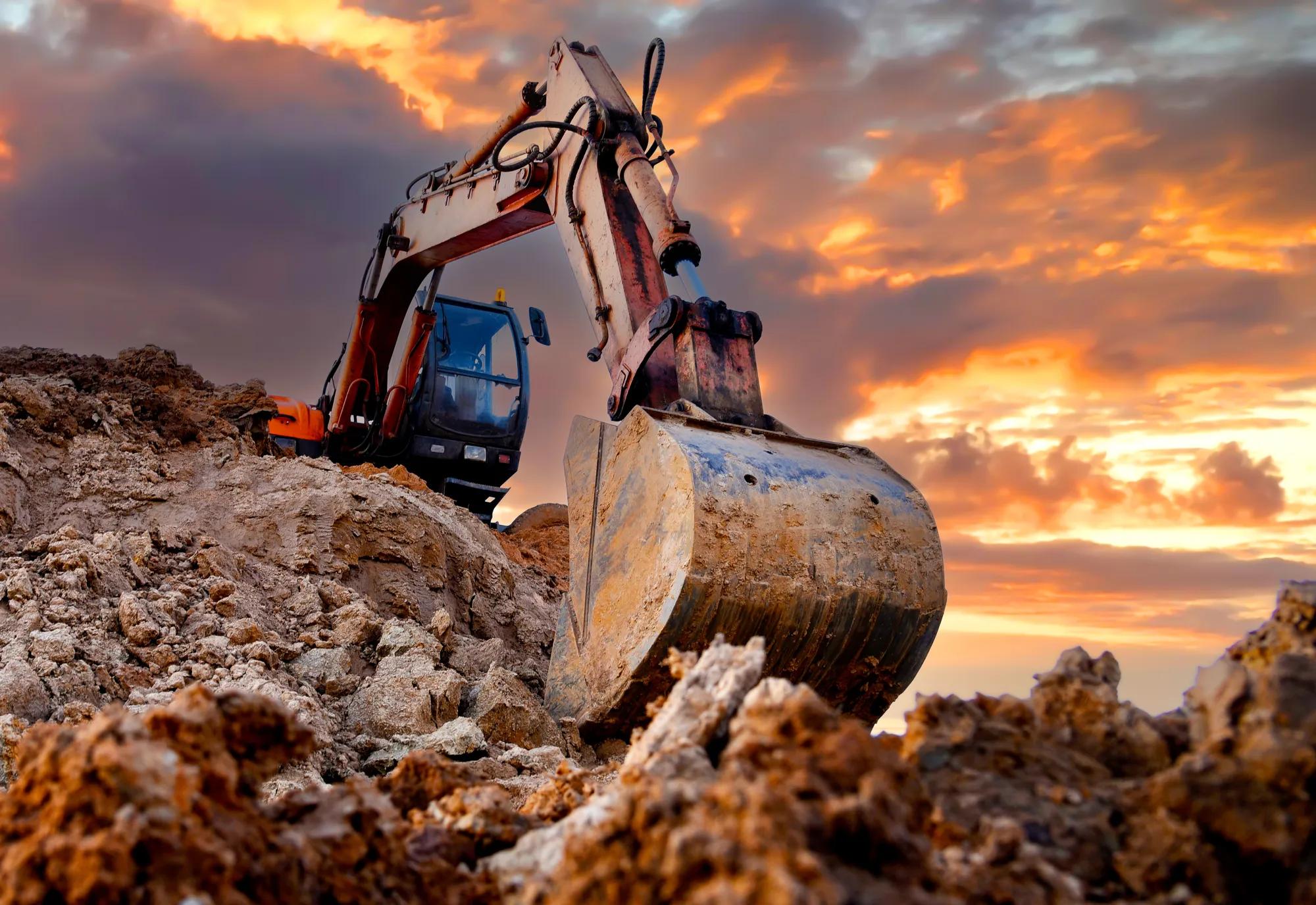Excavator on sunset. Open-pit mining. Backhoe dig ground in quarry. Heavy construction equipment on excavation on construction site. Excavator on groundworks. Construction machinery on Earthworks. AdobeStock_1224898085