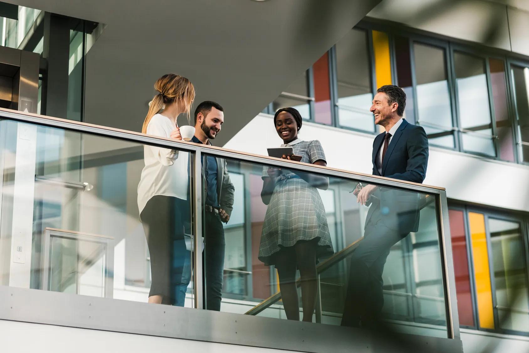 Happy coworkers talking on elevated walkway at office