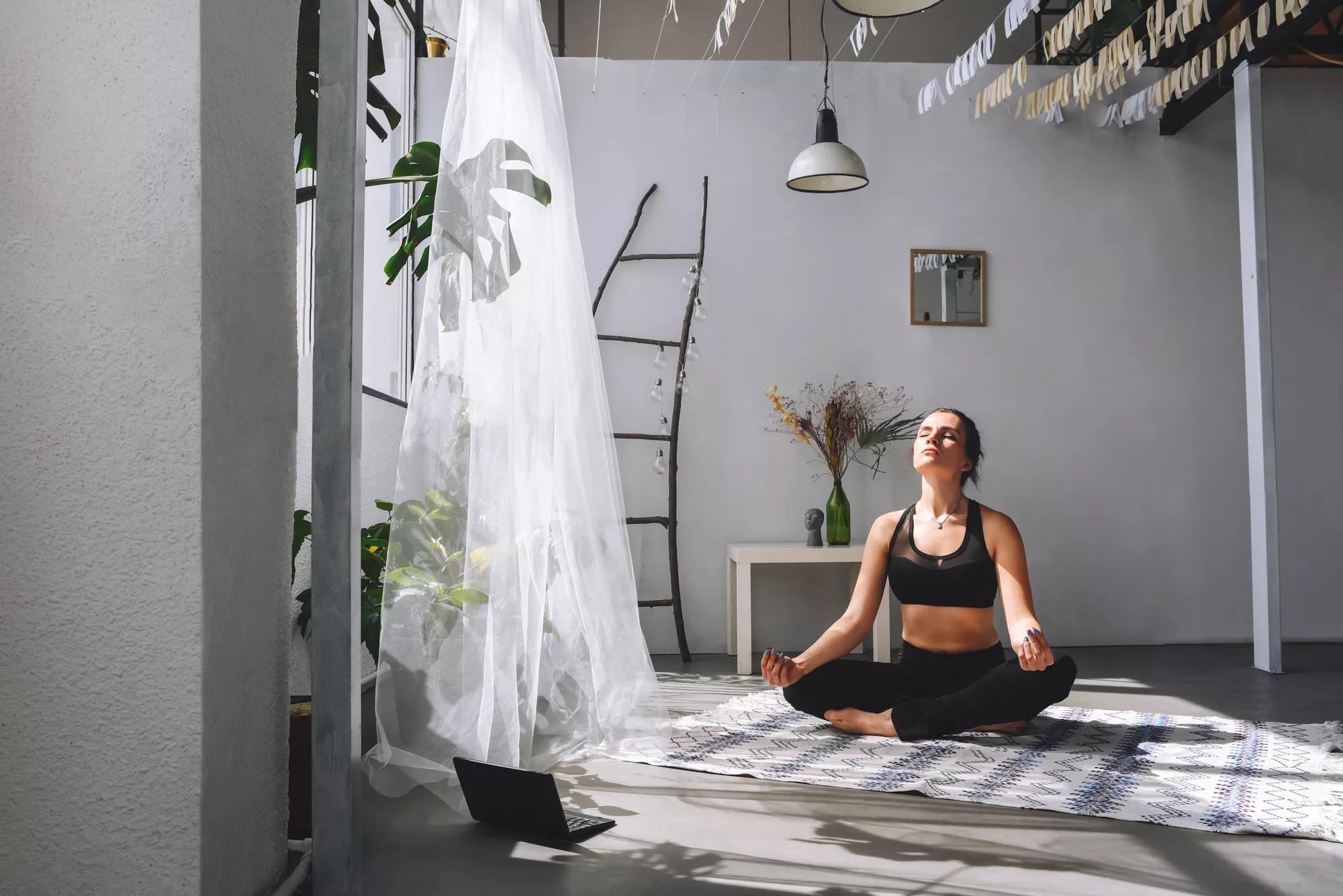 Girl meditates at home on video on a laptop. Sport at home. Meditation.