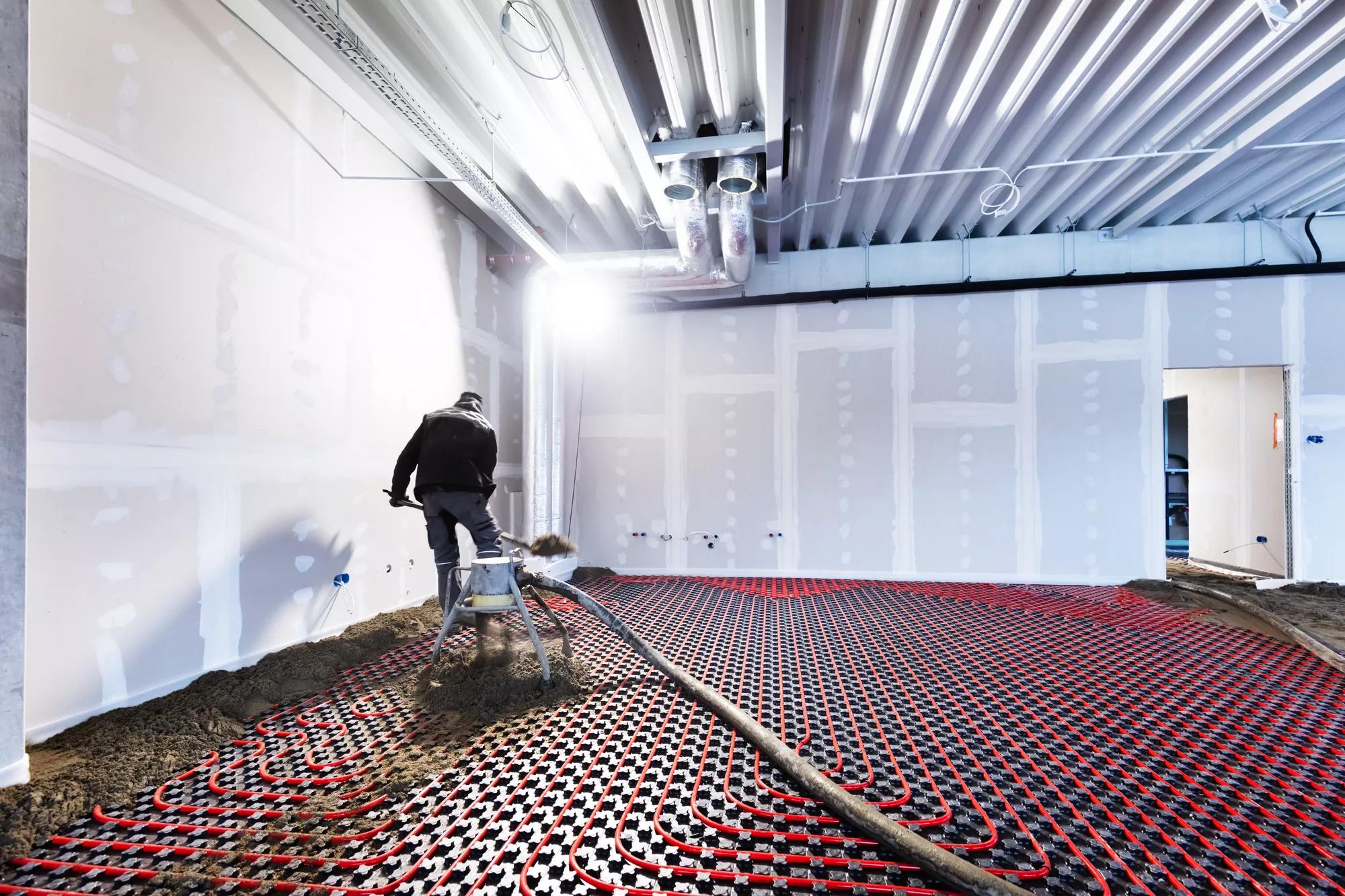 Worker installing floor heating in a new building. Interior design and finishing industry. Office and apartment