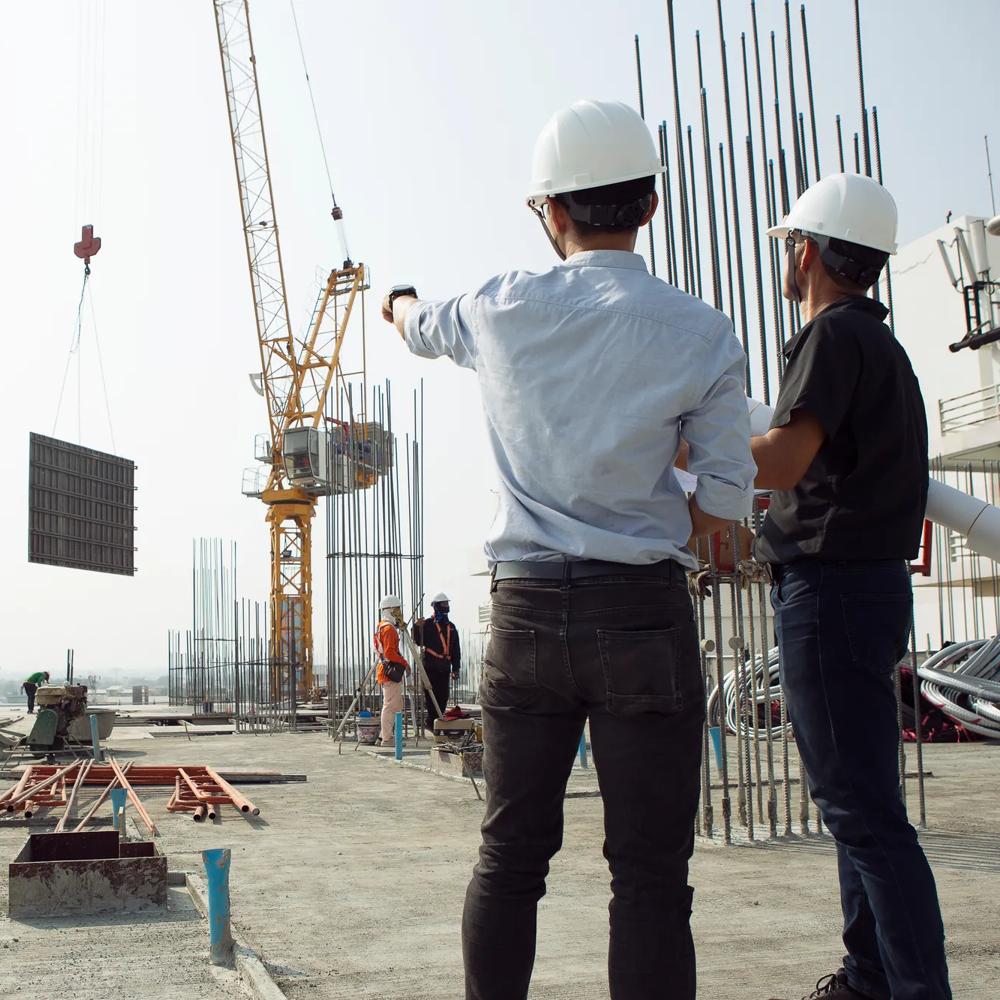 Two engineers work on the construction site. They are checking the progress of the work.