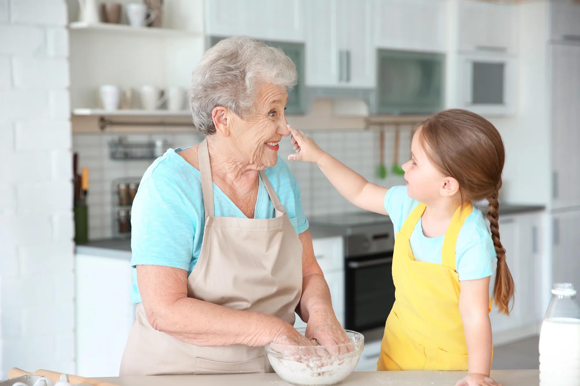 Cute little girl and her grandmother cooking on kitchen