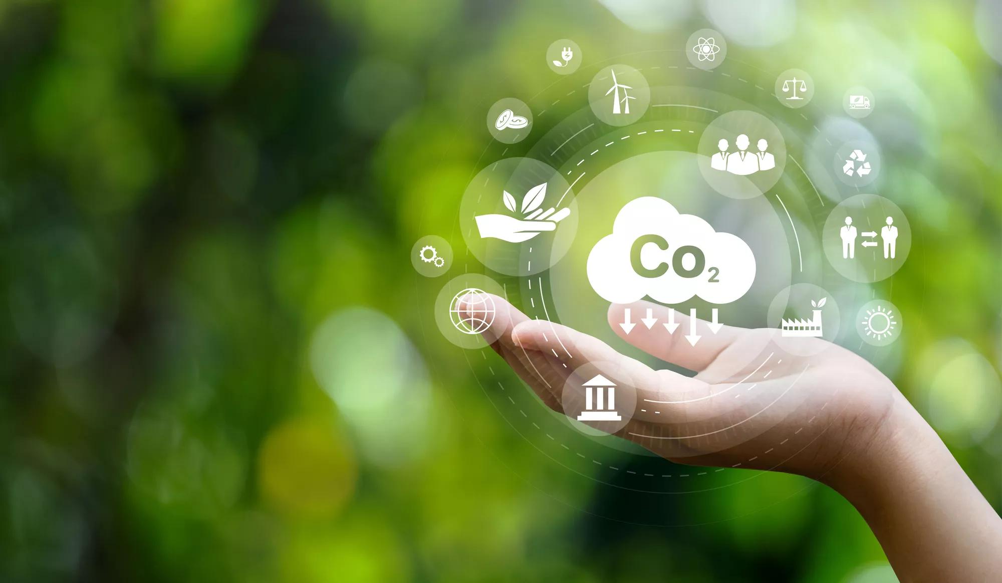 CO2 emission reduction concept in hand with environmental icons, global warming, sustainable development, connectivity and renewable energy green business background.