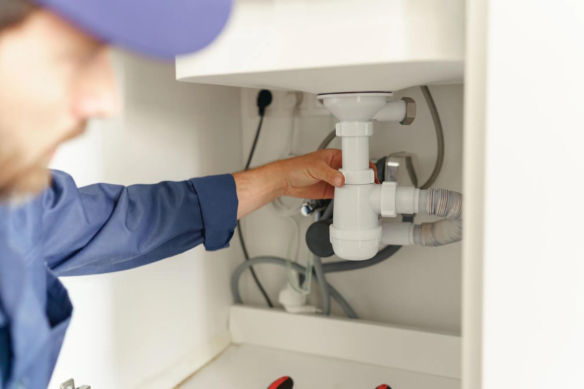 Close up of handyman installs a siphon pipe on the kitchen sink. High quality photo