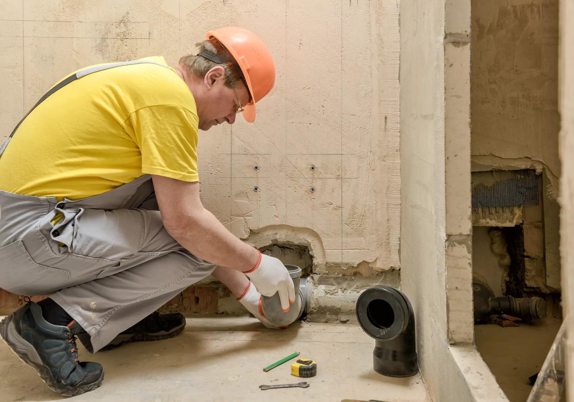 The worker is installing a sewage drain pipe to install the built-in tank of the toilet.