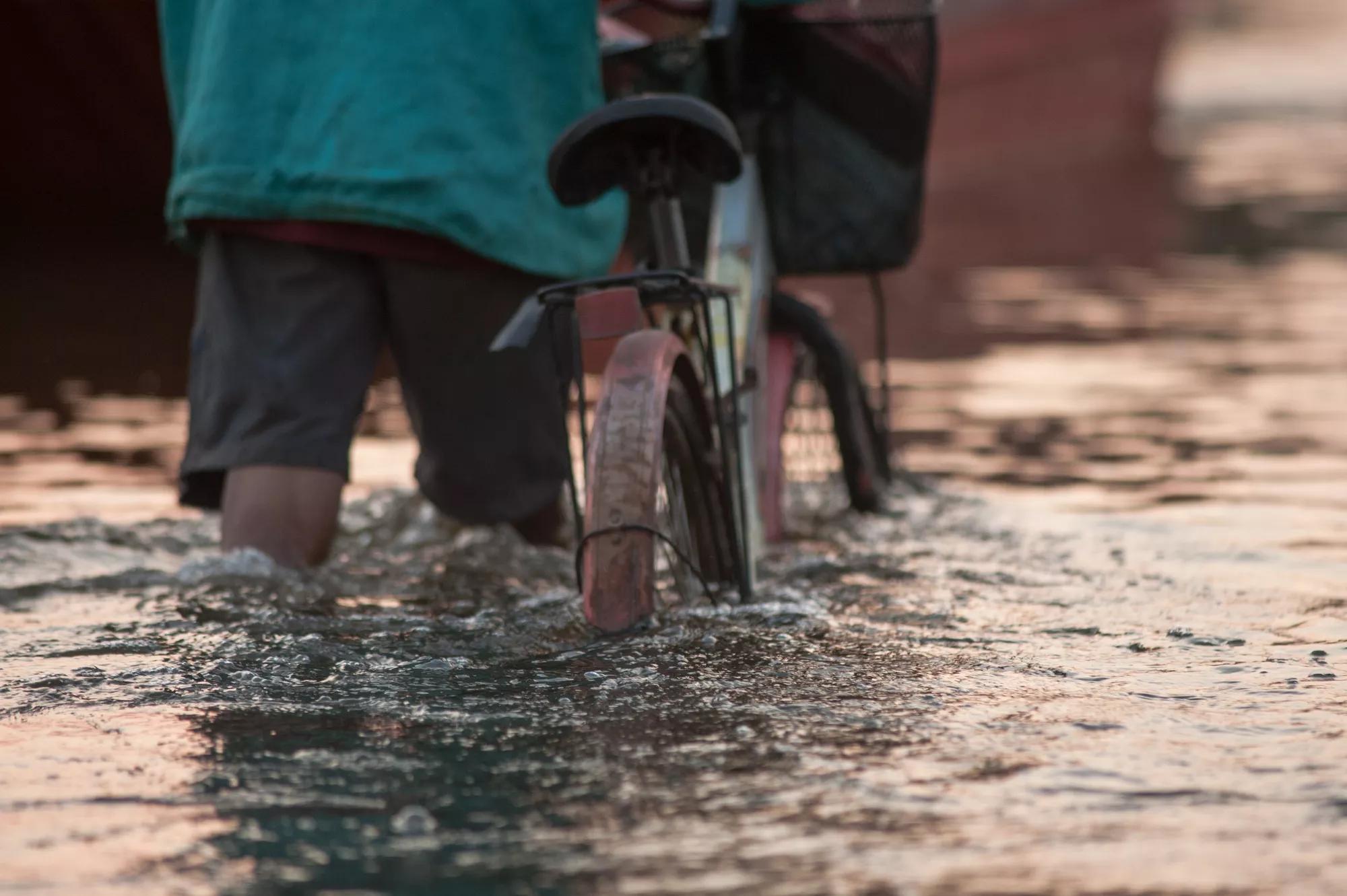 Biker on a flooded road during a flood caused by heavy rain, Thailand.