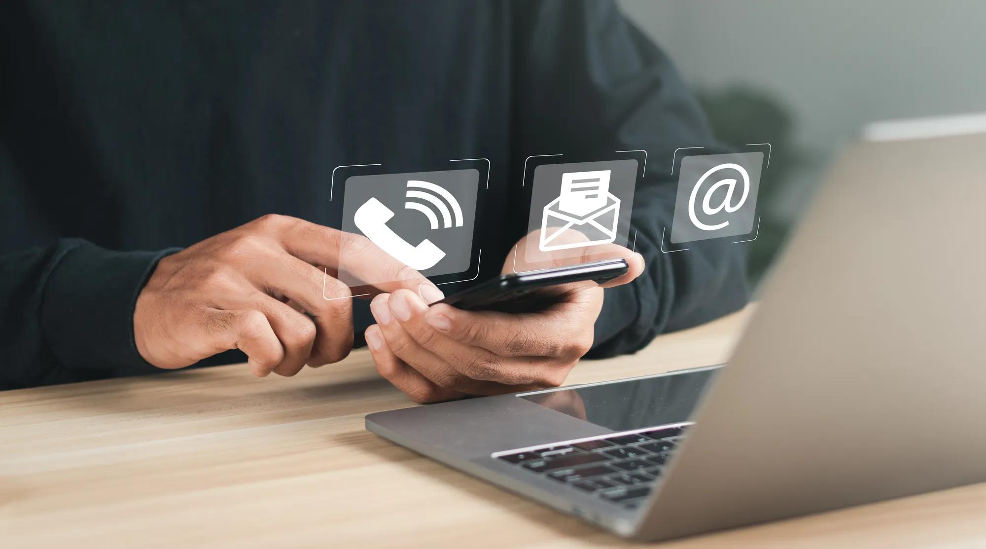 Businessman using laptop and smartphone with contact icons on virtual screen. searching web, browsing information, Contact us or Customer support hotline people connect.